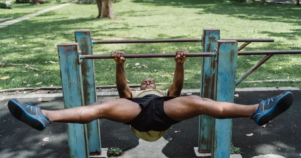 Homem treinando em barras paralelas de um parque, cenário de quem procura sites para aprender dips